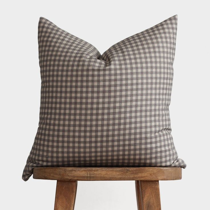 a grey and white checkered pillow sitting on top of a wooden stool