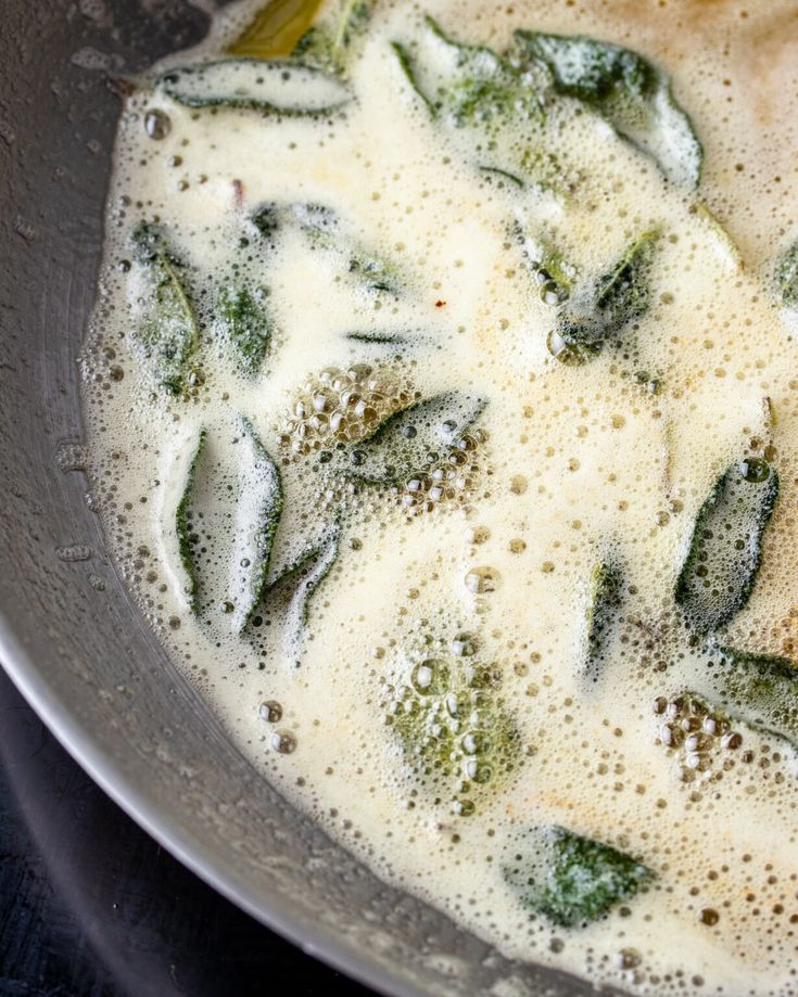 a pan filled with broccoli and cheese cooking on top of a stovetop