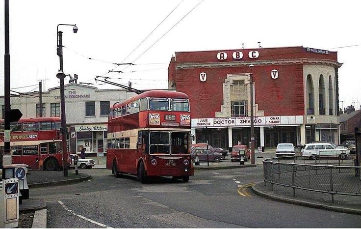 two red double decker buses driving down the street