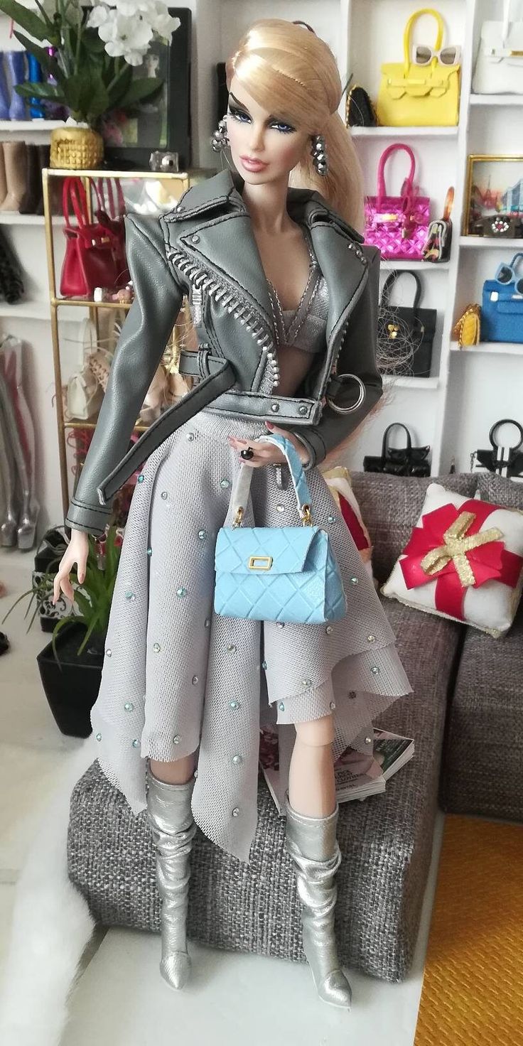 a barbie doll sitting on top of a couch holding a purse