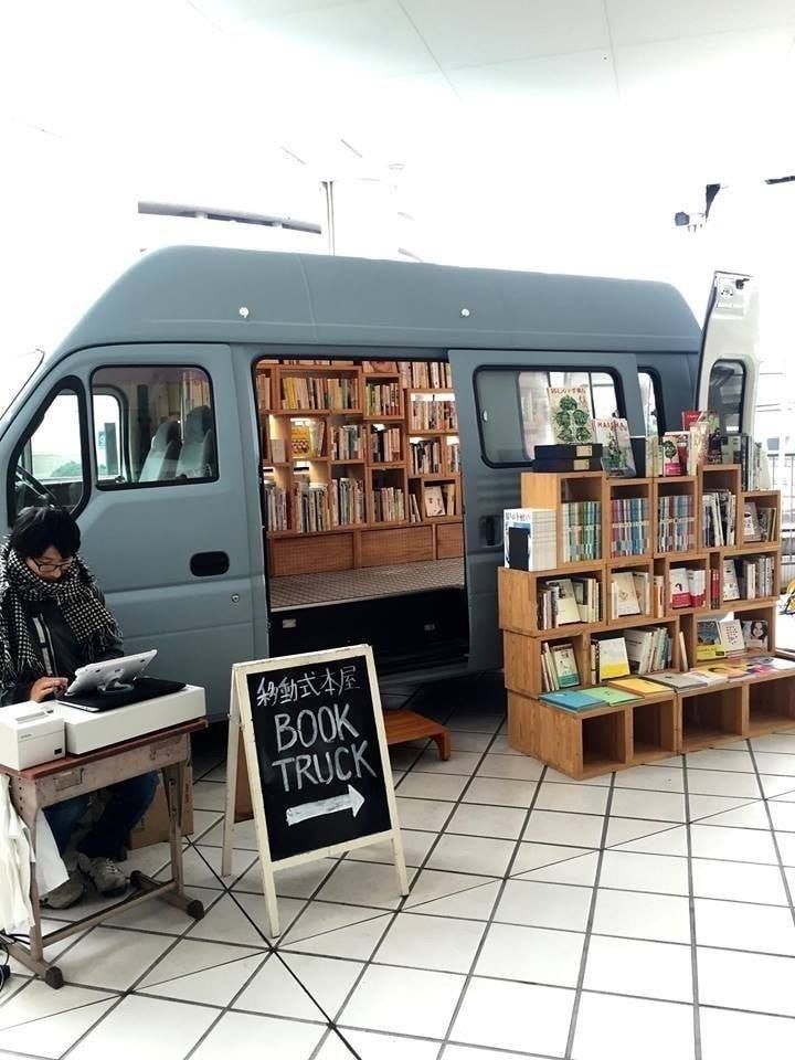 a person sitting in front of a book truck