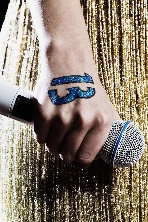 a person holding a microphone in their hand with the letter f on it's wrist