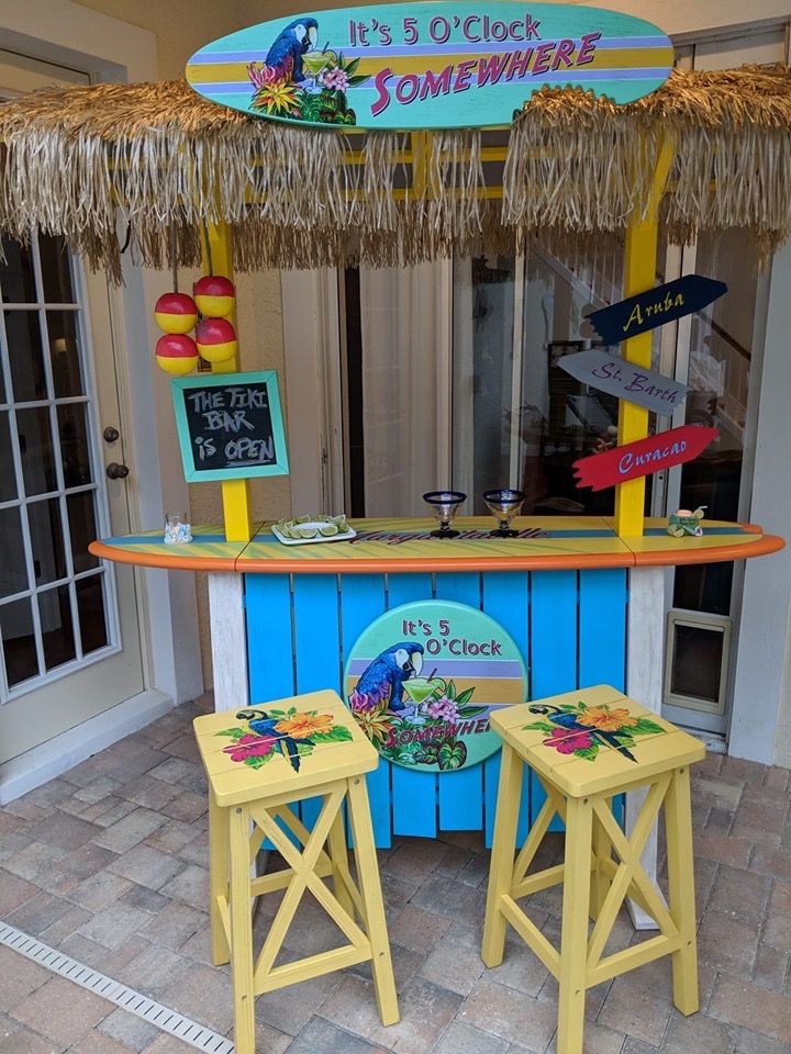 there is a small bar with two stools in front of it and a sign that says it's o'clock somewhere