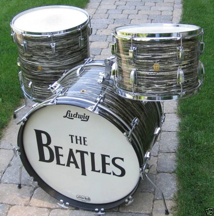 the beatles drum set is on display in front of some grass and brick walkways