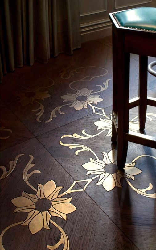 a wooden stool sitting on top of a hard wood floor next to a table and window