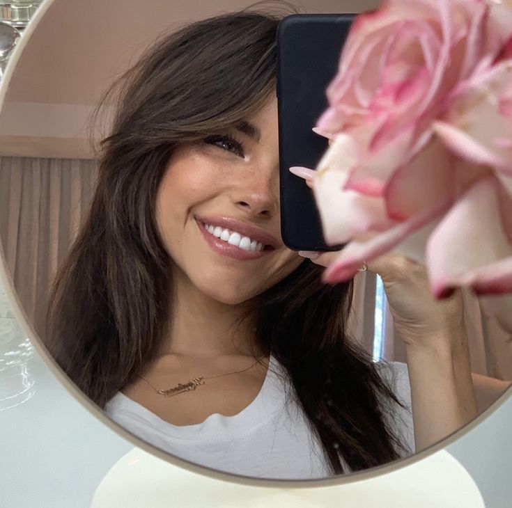 a woman taking a selfie in front of a mirror with a flower on it