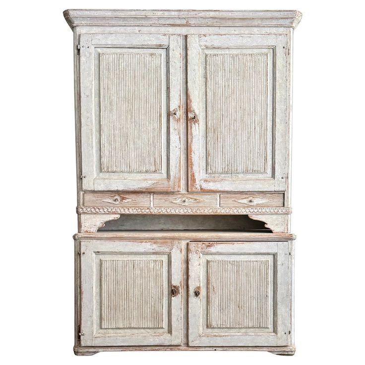 an old white cabinet with two doors and drawers on the bottom, sitting against a white background