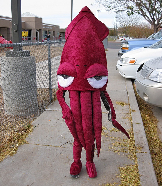 a person in an octopus costume is walking down the sidewalk next to a parking lot