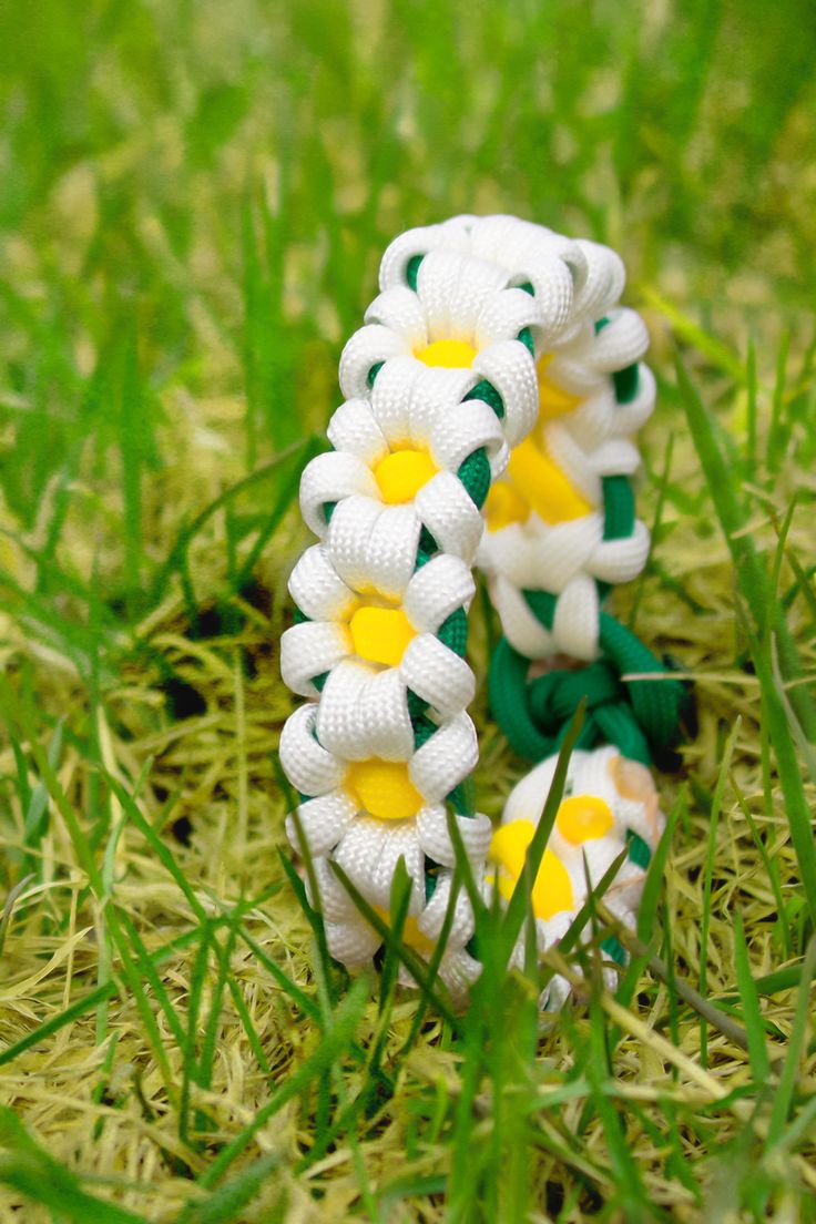 a white and yellow bracelet sitting in the grass