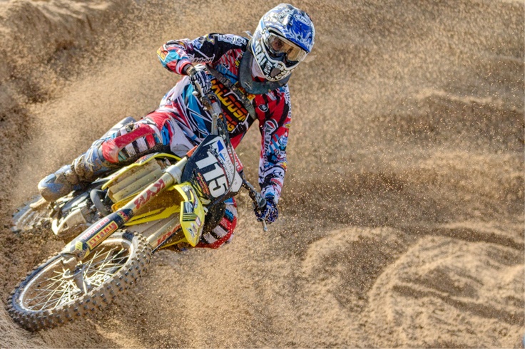 a man riding a dirt bike on top of a sandy field