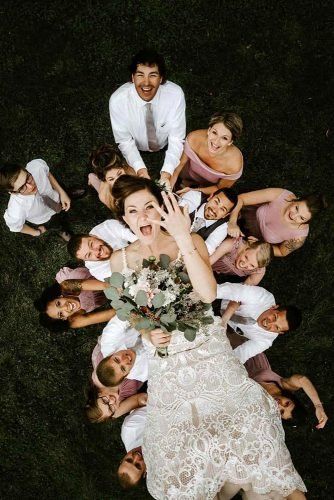 a group of people standing around each other with their hands in the air and one woman holding a bouquet