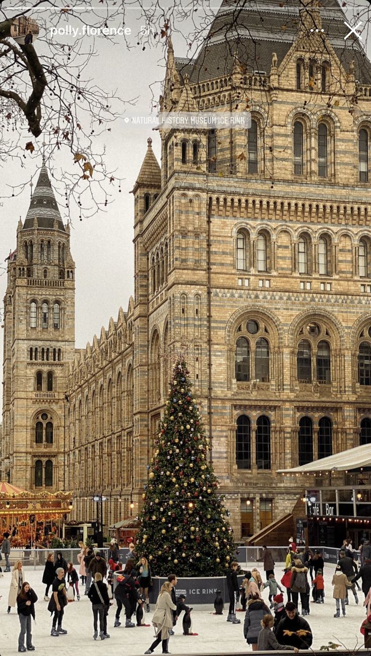 people are skating on an ice rink in front of a large building with a christmas tree