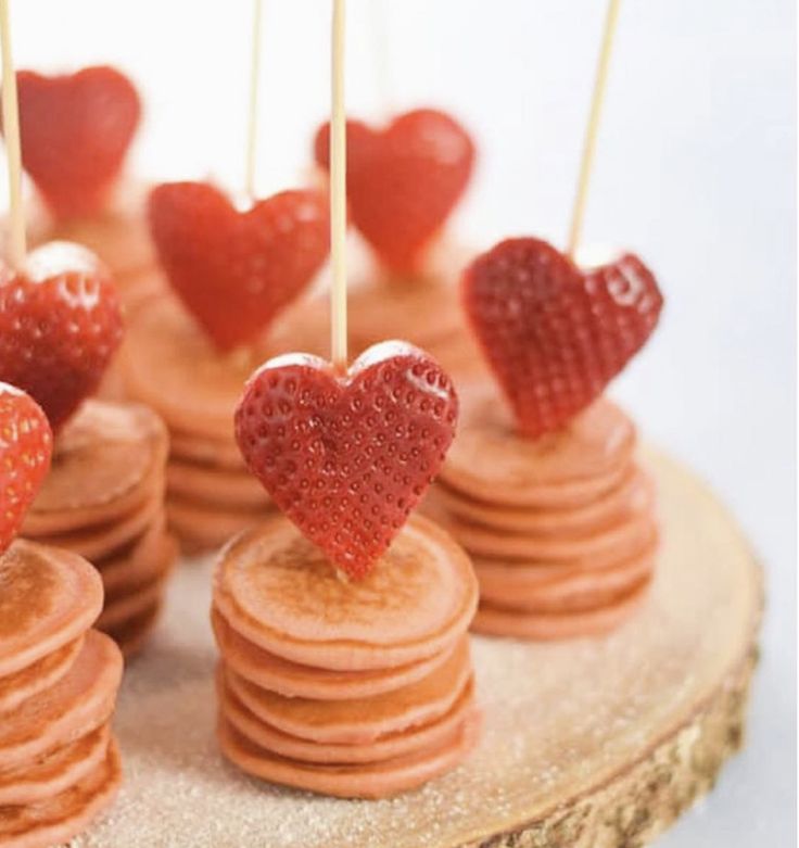 heart shaped strawberries are on top of pancakes with toothpicks in the shape of hearts