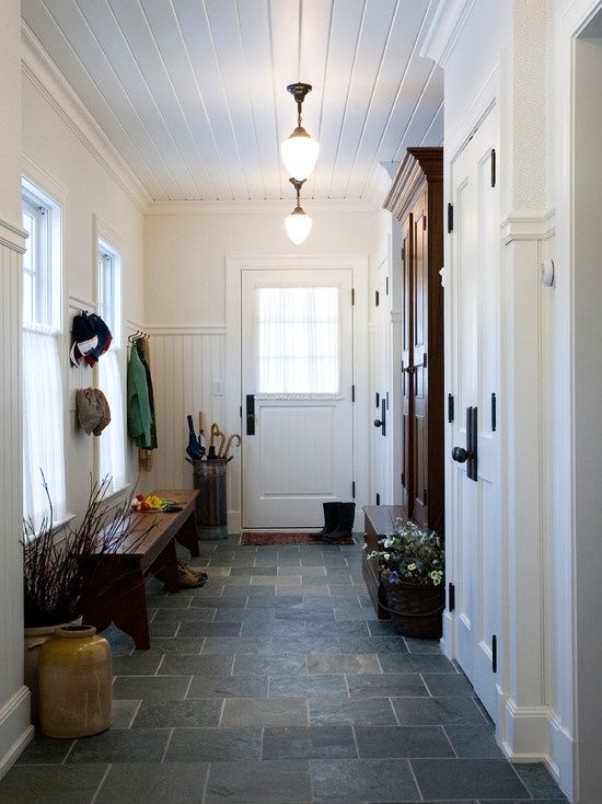 an entry way with two doors and a bench in the center, along with potted plants on either side