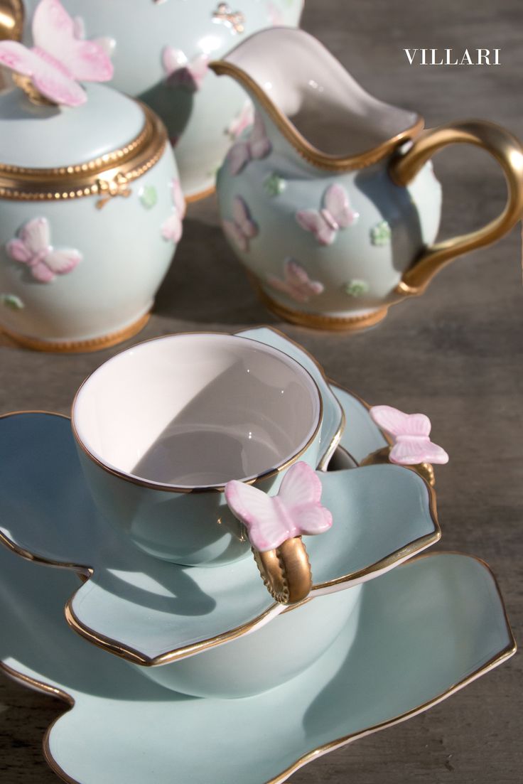 there is a tea set with pink flowers on the plate and butterfly decorations around it