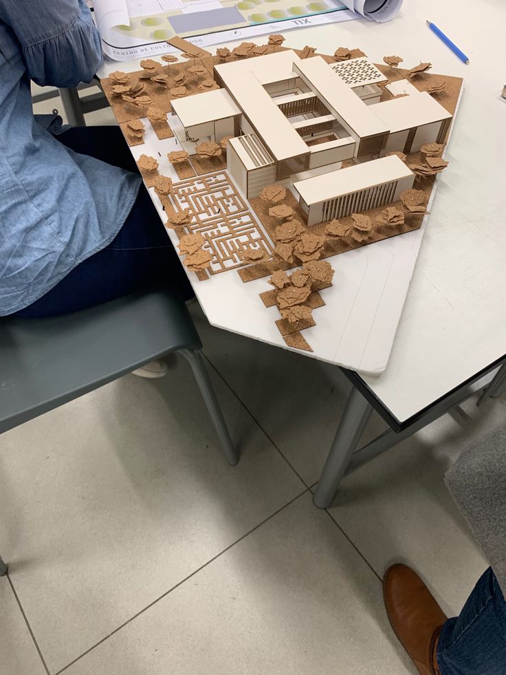 a person sitting at a table with a model of a building on it