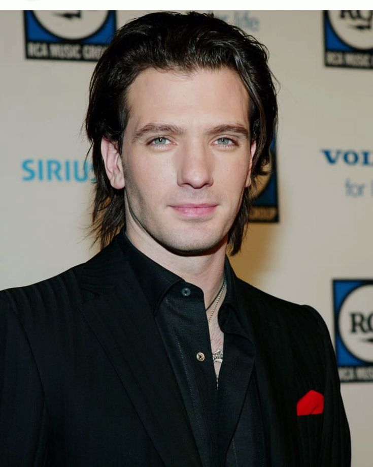 a man with long hair wearing a black suit