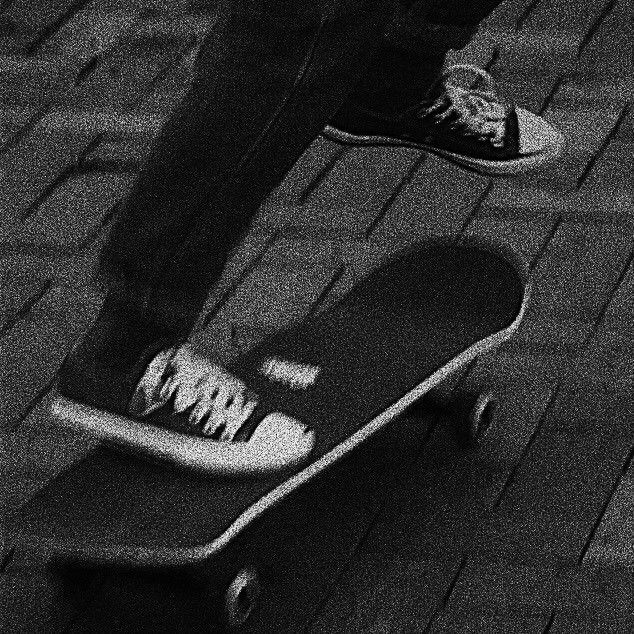 a person standing on top of a skateboard in the dark with their feet up