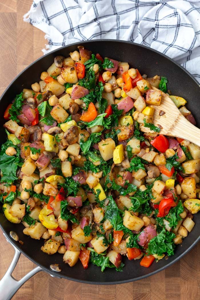 a skillet filled with vegetables on top of a wooden table