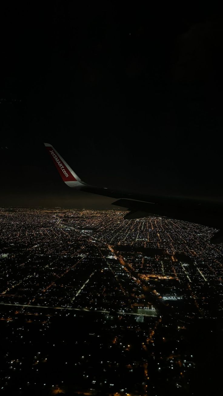 an airplane wing flying over a city at night