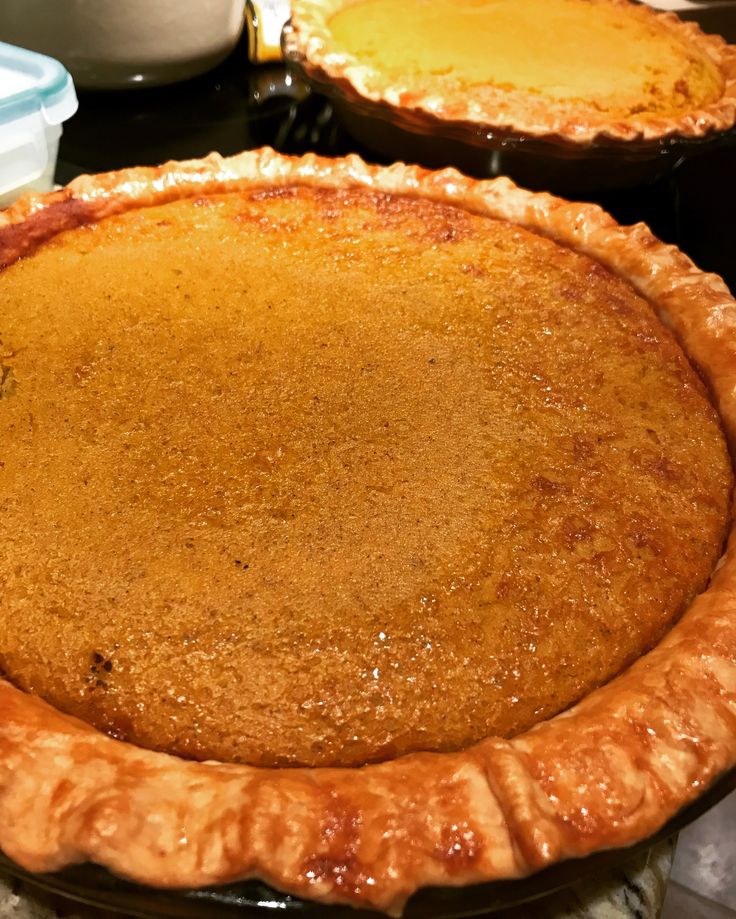 two pies sitting on top of a stove next to each other in pans