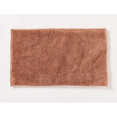 a brown bath mat on a white background