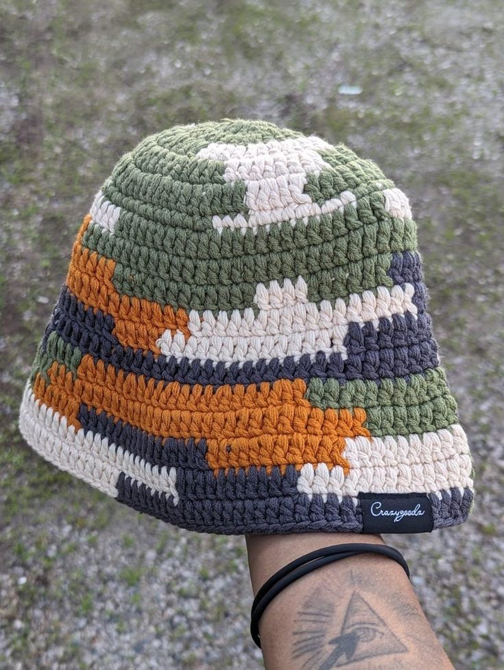 a person wearing a multicolored crocheted beanie on their left hand