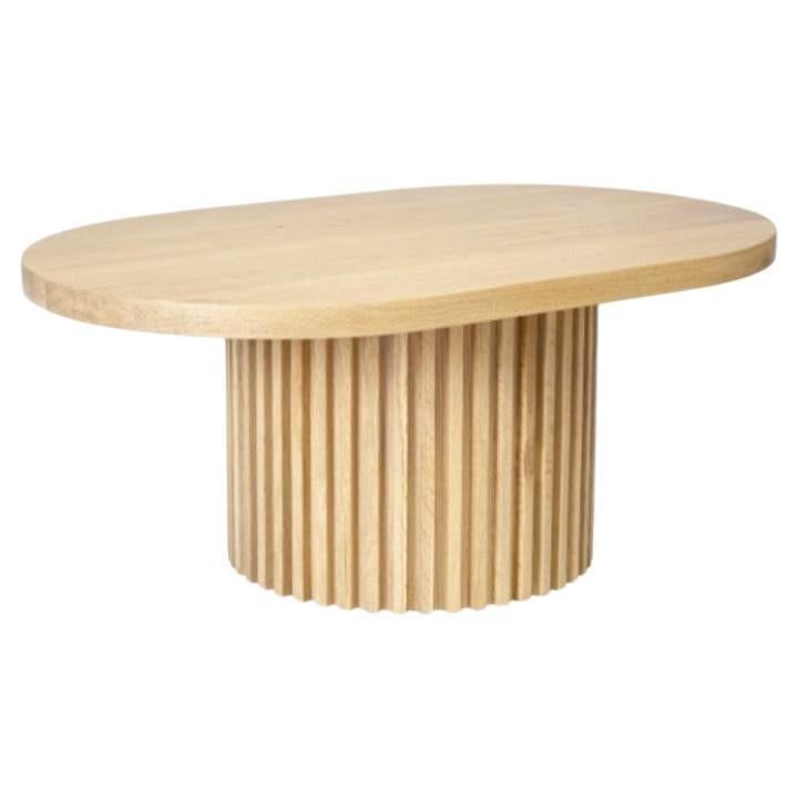 an oval wooden table with pleated edges and a circular base in the center, on a white background