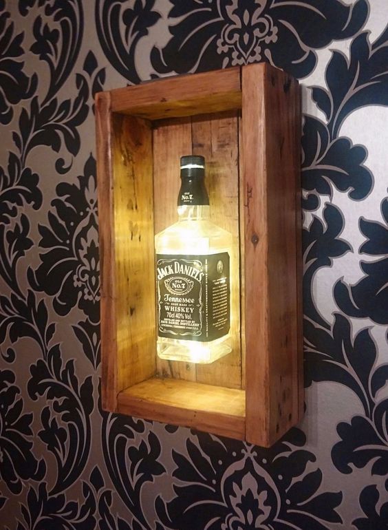 an illuminated bottle in a wooden box on the wall