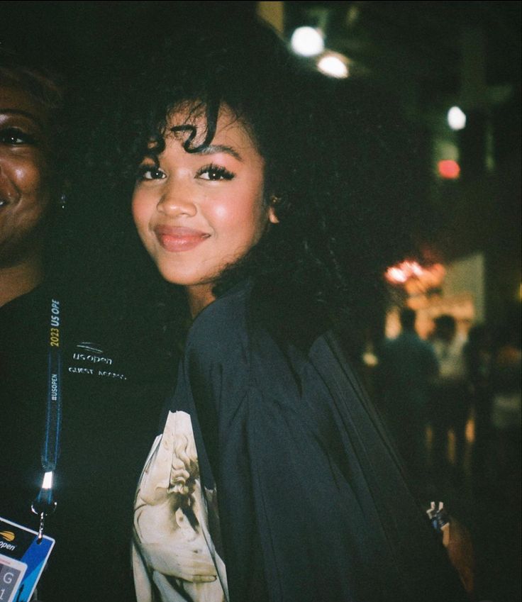 a woman standing next to a man in a black shirt and tie at an event