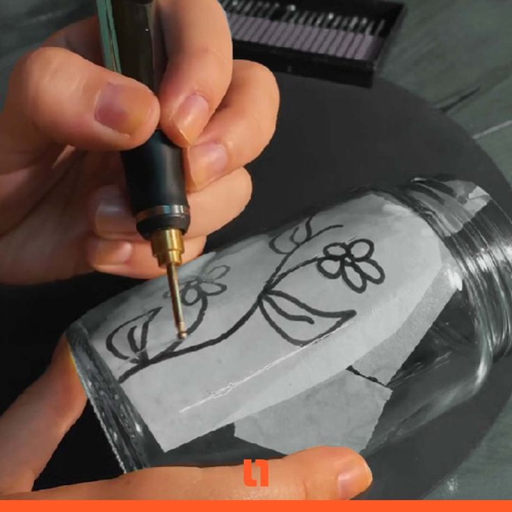 someone is drawing on a glass bottle with a pen