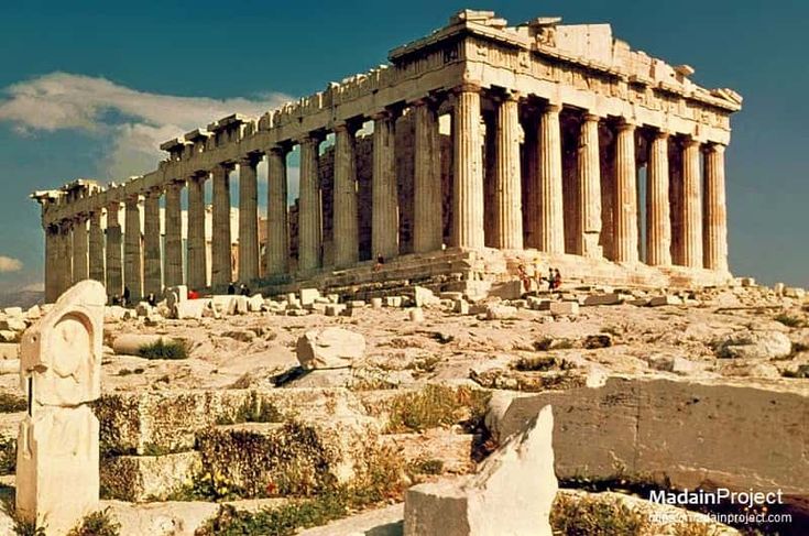 an ancient building with columns and pillars in the middle of a rocky area surrounded by rocks