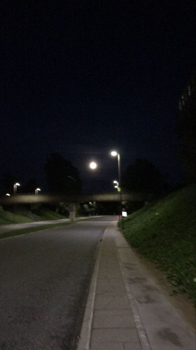 an empty street at night with the lights on and no cars driving down the road