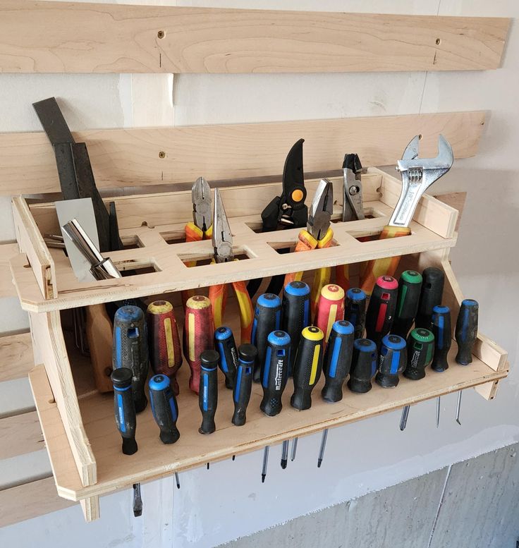 a bunch of tools that are sitting on a shelf in a workbench with pegs and pliers