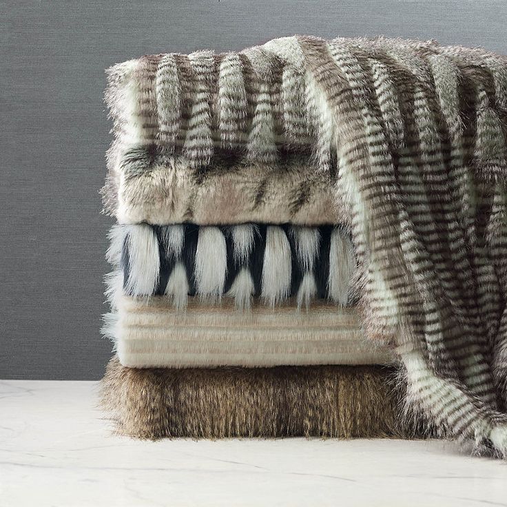 a pile of blankets sitting on top of a white table next to a gray wall