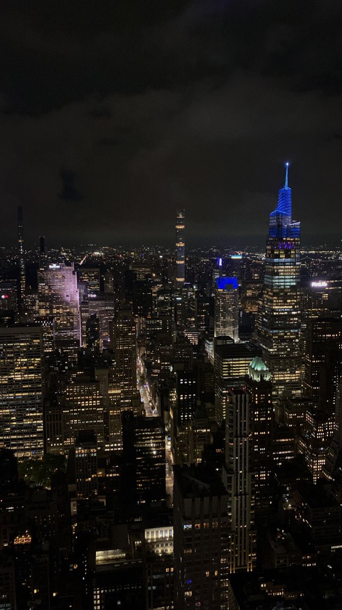 an aerial view of the city at night with skyscrapers lit up in blue and white