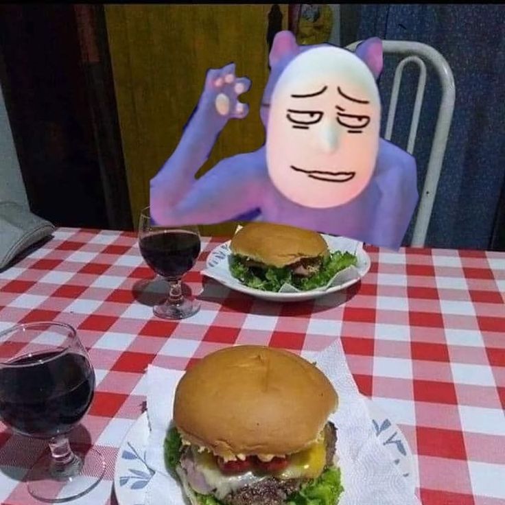 two plates with hamburgers on them sitting on a table next to a glass of wine