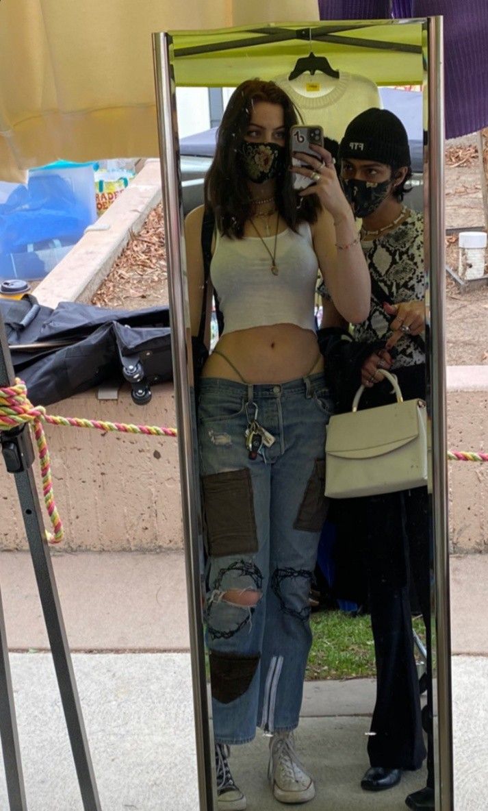 a woman taking a selfie in the mirror with her cell phone while standing outside