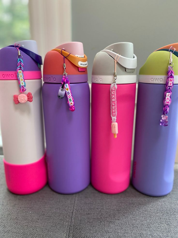 four different colored water bottles sitting next to each other on the floor in front of a window