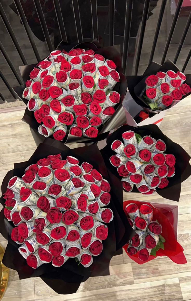 red roses are arranged on top of each other in black paper wrappers and vases