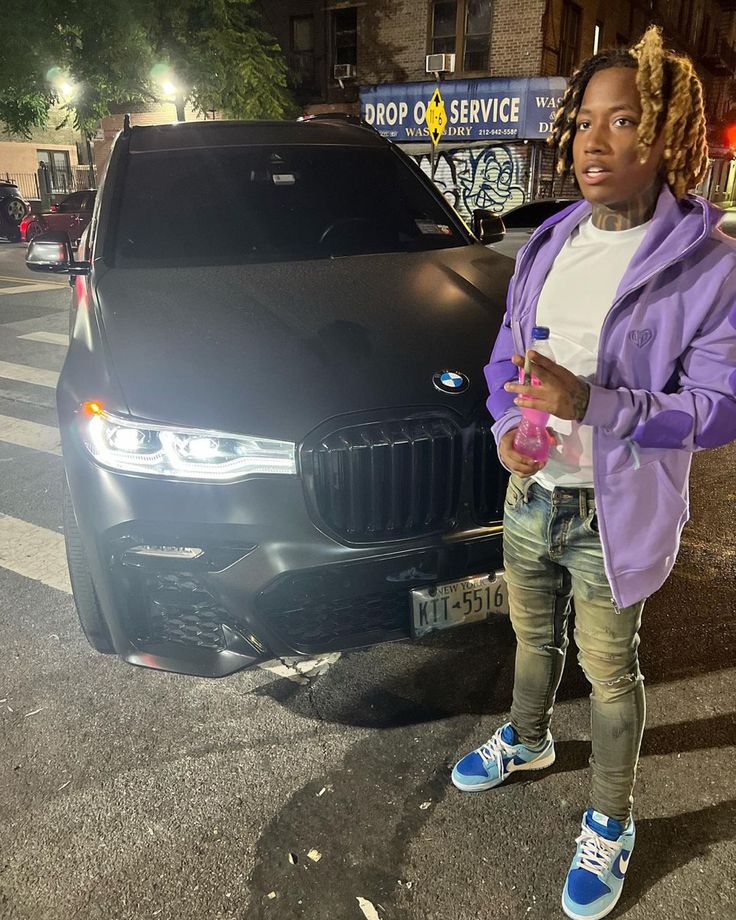 a woman standing in front of a black car