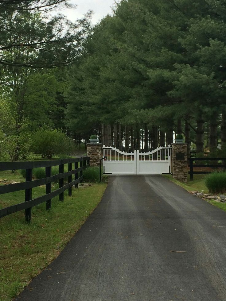 a gated driveway leading into a wooded area