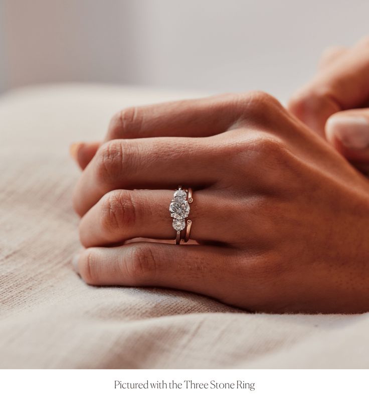 a woman's hand with a diamond ring on her left hand and the other hand holding an engagement ring