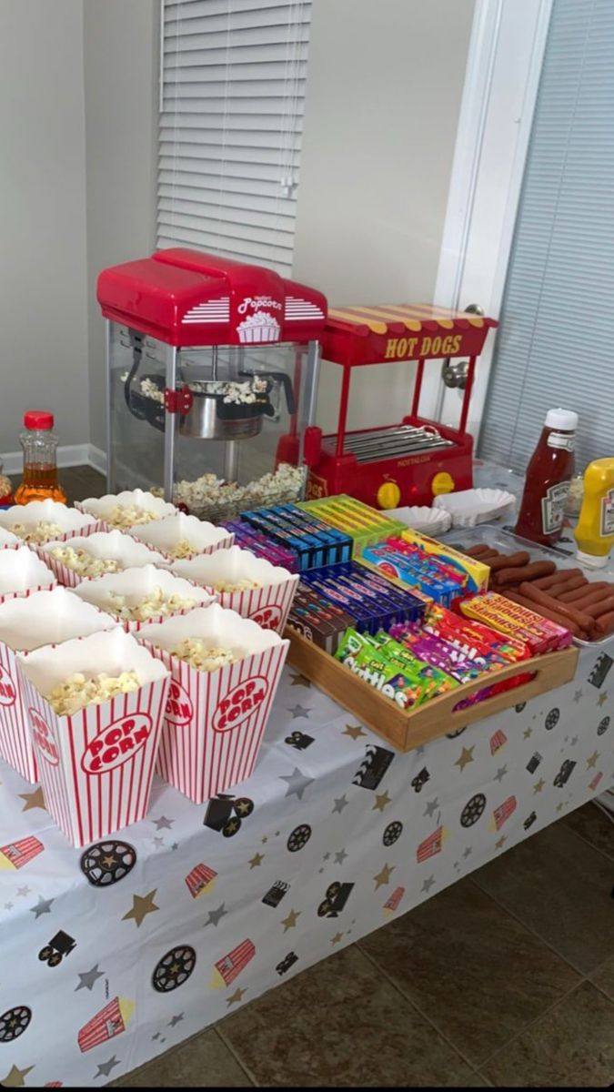 a table topped with lots of cupcakes next to a candy bar filled with popcorn