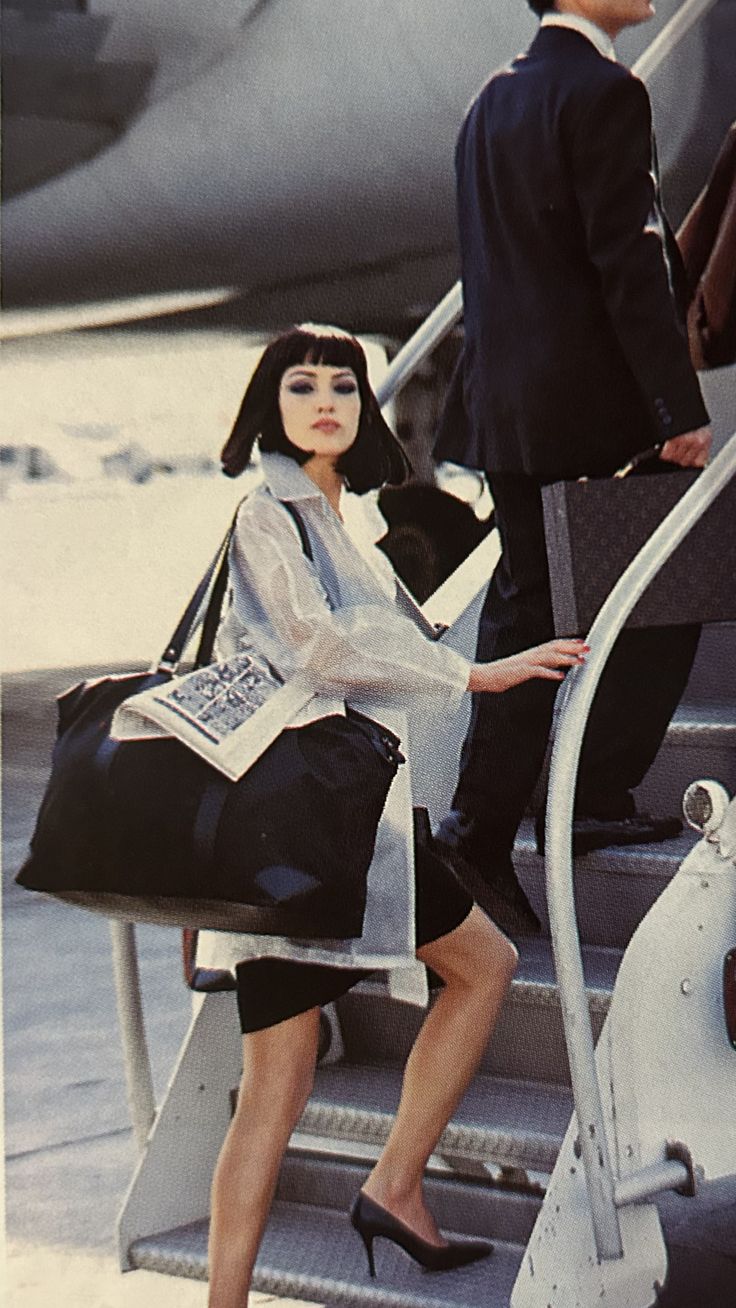 a woman sitting on the steps of an airplane next to a man in a suit and tie