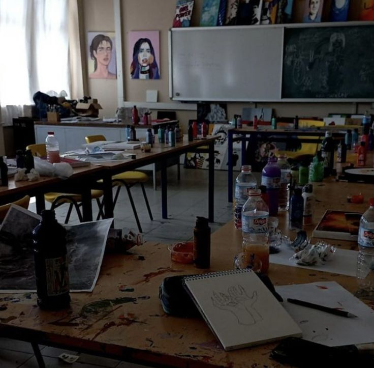 an empty classroom with desks and paintings on the walls