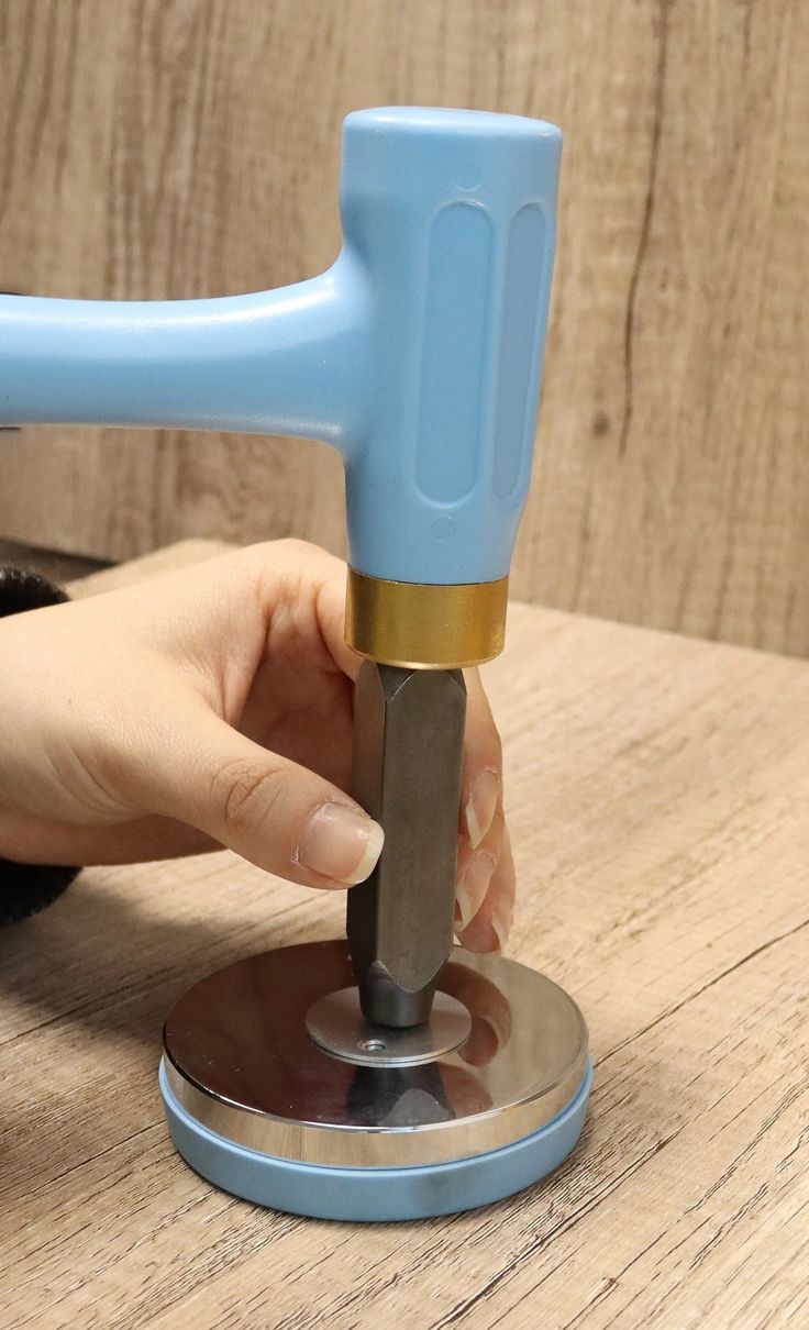 a person is using a small tool on a wooden table