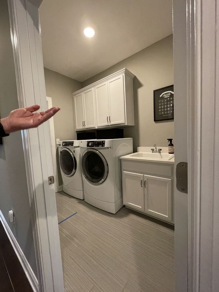 a person is holding out their hand in front of a washer and dryer