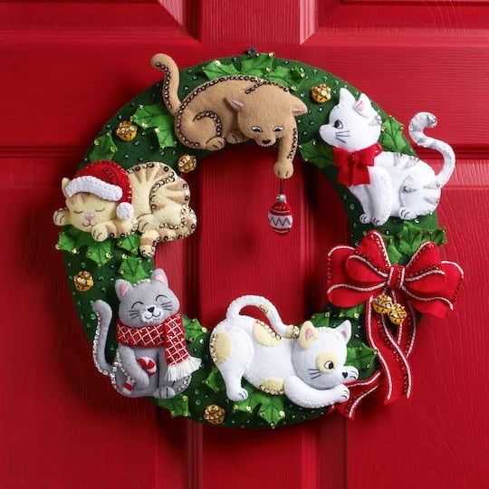 a christmas wreath with cats and kittens hanging from it's side on a red door