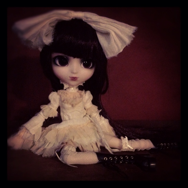 a doll sitting on top of a table next to a remote control